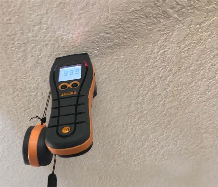 Moisture meter detecting water levels in dry wall.