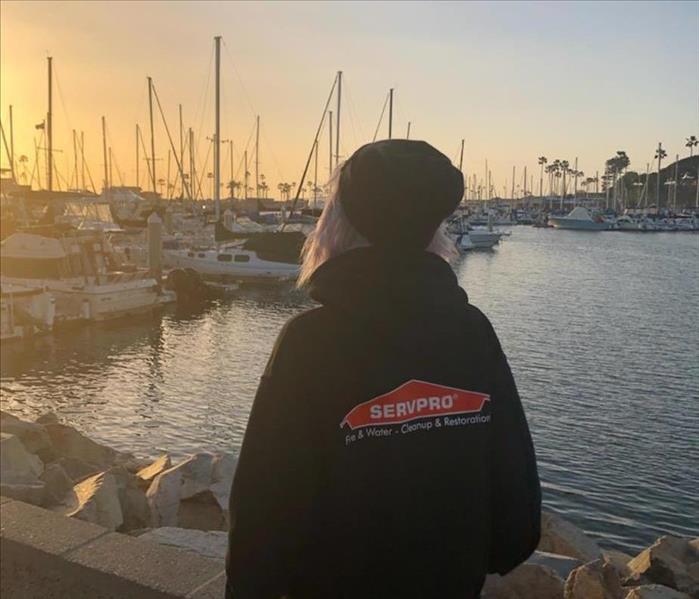 Woman wearing black SERVPRO hoodie while looking into the bay docked with boats.
